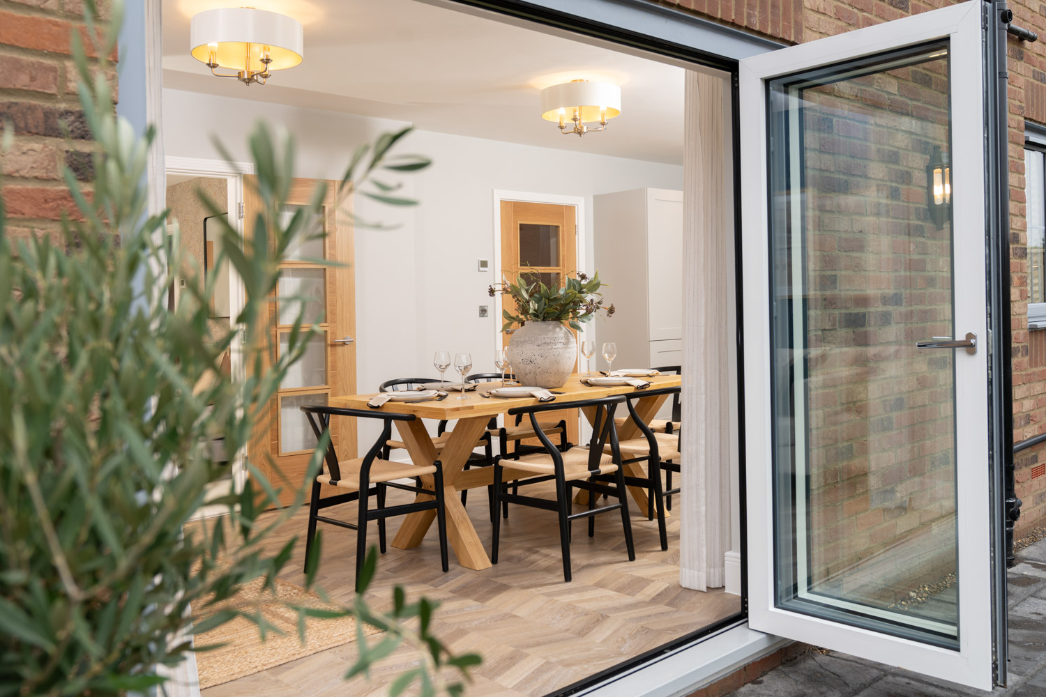Open doors look into dining area with dining table and chairs and wooden flooring